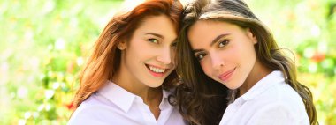 Açık havada kadın kız arkadaşlarla bahar pankartı. Yeşil arka planda kameraya bakarken birlikte poz veren iki güzel kadın..