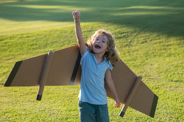 Pojkbarn drömmer och reser. Pojke med flygplansleksak utomhus. Glada barn leker med leksaksflygplan utomhus på sommarfältet. Resor, semester och frihet barn koncept. — Stockfoto