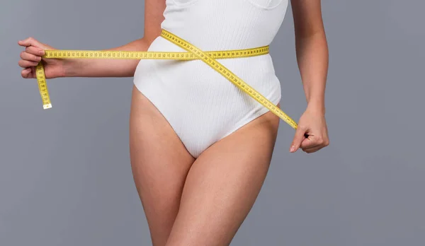 Concepto de alimentación saludable y dieta. Chica joven con cintura perfecta con una cinta métrica. De cerca.. —  Fotos de Stock