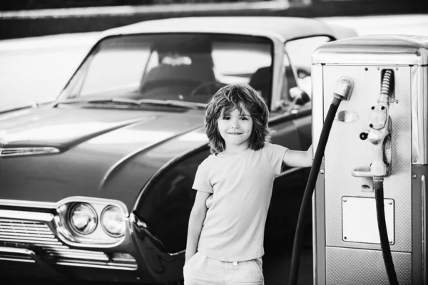 Retrobensinstation. Le Kid pojke på bensinstationen. Väntar på bränsle. Grabben tankade veteranbil på bensinstationen. Bränslepåfyllning med bensin. — Stockfoto