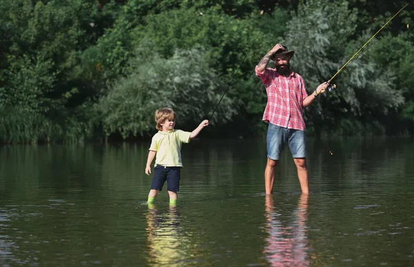 Apa és fia horgásznak. Apa a fiával a folyón élvezi a horgászbotokat.. — Stock Fotó