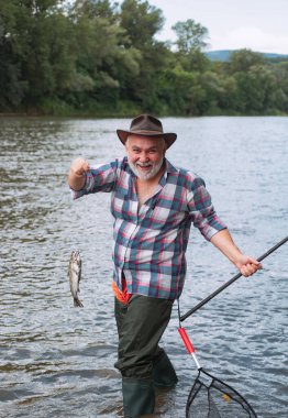Kahverengi alabalık balık ağına yakalanmış. Alabalık. Balık tutmak için. Balık tutmak - rahatlatıcı ve zevkli bir hobi. Balık kafası ve olta kancası. Nehir grileşiyor kancada.