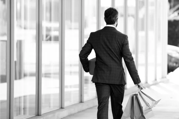 Πίσω όψη του ανθρώπου των επιχειρήσεων ποζάρουν με τσάντες ψώνια εξωτερική. — Φωτογραφία Αρχείου