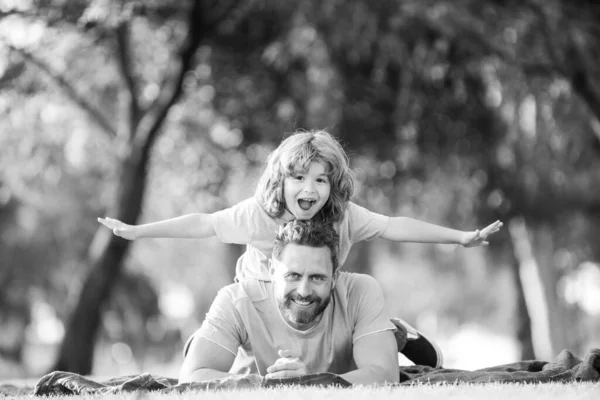 Konzept der freundlichen Familie. Vater und Sohn liegen im Sommerpark auf Gras und verbringen Zeit im Freien. — Stockfoto