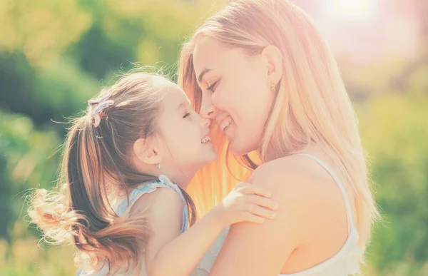 Kinderliebe. Glücklich lächelnde Mutter mit ihrer kleinen Tochter vor dem Hintergrund des Sonnenuntergangs. glückliche Mutter umarmt ihre Tochter. — Stockfoto