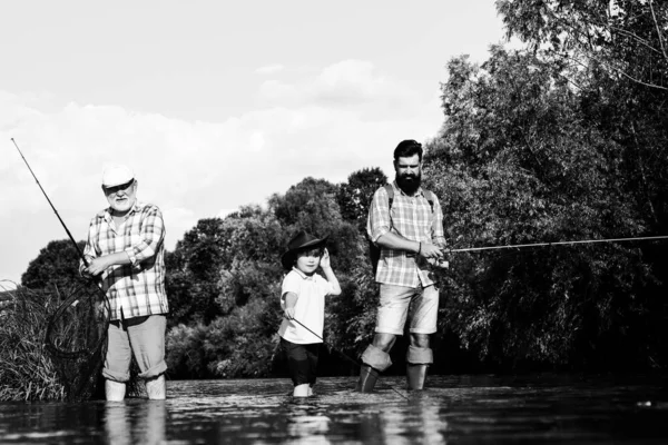 Fishing. Little boy fly fishing on a lake with his father and grandfather. Grandfather and father with cute child boy are fishing. Fly fishing. Hobby and sport activity. Male multi generation family.