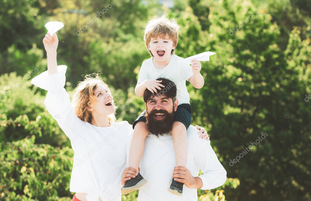 Father mother and son camping. Dad mom and his child son are playing on sky background. Happy child with parents playing with toy wings against summer sky background.