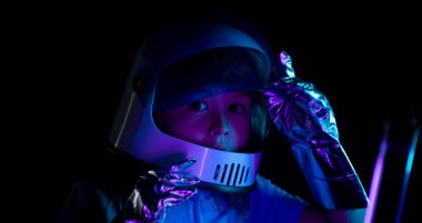 Çocuk astronot kostümü giymişti. Heyecanlı çocukların yüzlerini neon rengine yakın tut.