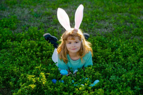 Παιδιά που κυνηγούν πασχαλινά αυγά στον κήπο. Παιδιά με πολύχρωμα αυγά στο γρασίδι. Το αγοράκι παίζει έξω. Αυγά για κυνήγι παιδιών. — Φωτογραφία Αρχείου