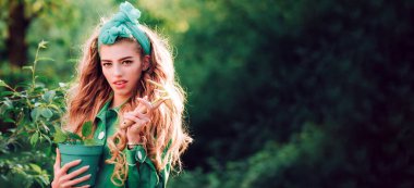 Pankart ya da web sitesi başlığı olarak güzel kadın yüzü olan bahar tasarımı, kopyalama alanı. Güzellik kraliçesi meyve bahçesinde vakit geçiriyor. Saksıya çiçek eken kadın.