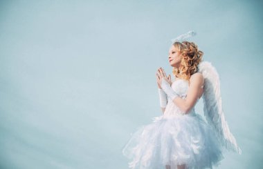 Melek. Sevgililer günü aşk tanrısı. Cennete. Mutlu genç melek kız duası. Kutlama Sanat Kutlama Kartı. Beyaz melek elbisesi içindeki haleli kız melek. Bulutların üzerindeki sevimli genç aşk tanrısı - cennet arkaplanı.