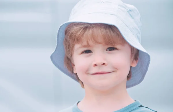 Nära porträtt av en pojke med långt hår i hatt. Ett lyckligt litet barn som ler. Förtjusande barn som har roligt. Ett sorglöst barn. Barnpassning. Närbild. Vilken rolig dag. Lilla söta pojke ler. — Stockfoto