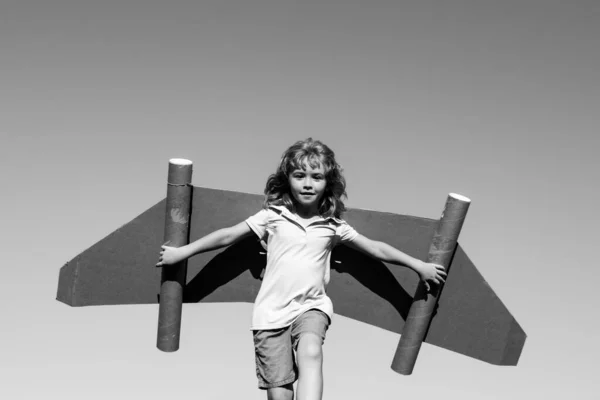 Criança feliz brincando com asas de brinquedo contra o fundo do céu de verão. Sucesso infantil, conceito de líder e vencedor. — Fotografia de Stock