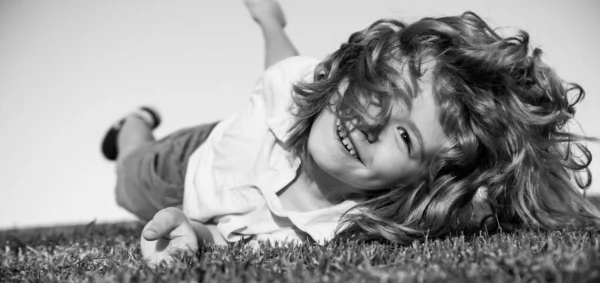 Joyeux enfant jouant sur l'herbe verte. Enfant drôle en plein air dans le jardin de printemps. Concept de journée enfants. — Photo