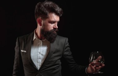 Sakallı yakışıklı adam elinde bir bardak konyak tutuyor. Tatma ve degukasyon konsepti. Barmen ya da barmen konyak servisi yapar..