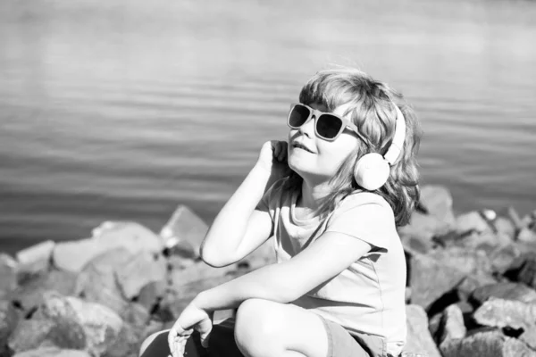 Niño despreocupado con auriculares. Escuchando el concepto de música. Niño en auriculares al aire libre. Paseo de verano. —  Fotos de Stock