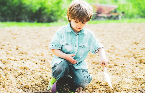 儿子种花。花园工具。在花园附近的花园里干活的孩子. — 图库照片
