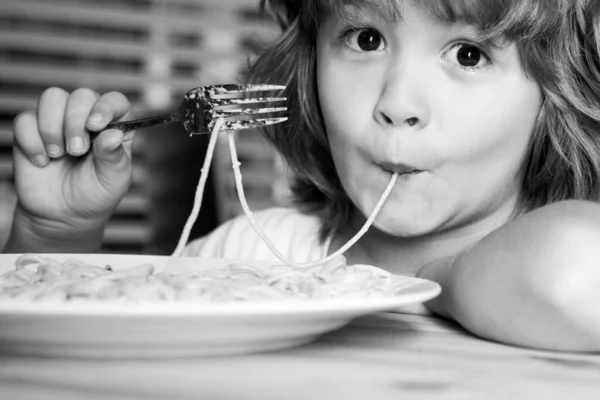 Porträtt av en liten blond pojke som äter pasta, spaghetti, närbild. Söta barn ansikte. Positivt känslomässigt barn. — Stockfoto