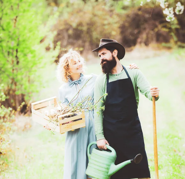 Ein Bauer und seine Frau stehen auf ihrem Feld. Das Bauernpaar genießt die frühlingshafte Natur und kümmert sich um seine Pflanzen. Erdkonzept. — Stockfoto