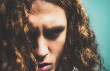 Ciddi yüzlü ve vahşi stili olan bir adam. Berber dükkanı reklamı. Mavi arka planda yakışıklı bir adamın portresi..