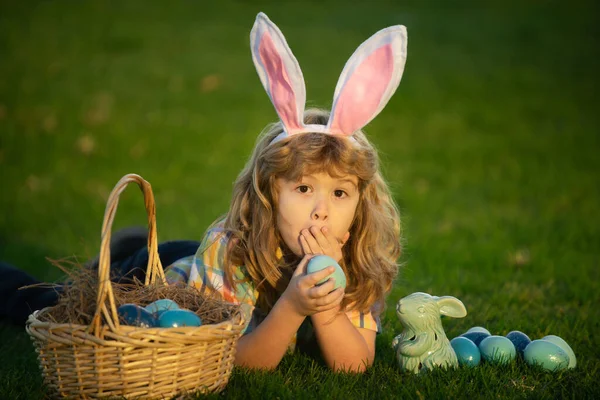 Wielkanocne polowanie w ogrodzie. Chłopiec bawiący się na polu, polujący na pisanki. Dziecko króliczek chłopiec z króliczych uszu królika. — Zdjęcie stockowe