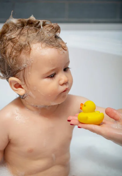 Dziecięca kąpiel. Szczęśliwe dziecko biorące kąpiel bawiąc się bańkami z pianki. Małe dziecko w wannie. Uśmiechnięty dzieciak w łazience z zabawkową kaczką. Mycie i kąpiel niemowląt. Opieka nad dziećmi i higiena. — Zdjęcie stockowe