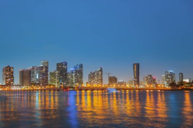 Miami şehri. Alacakaranlıkta deniz üzerinde gökdelenlerle Miami gökyüzü manzarası. Sanset 'te gece.