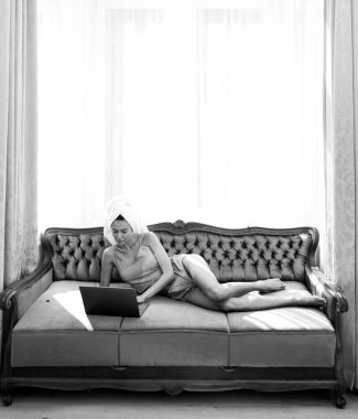 Uyandıktan sonra yatak odasında dizüstü bilgisayar kullanan beyaz bornozlu ve havlulu genç ve güzel kadınlar. Evde ya da otel odasında yatakta tasasız kadın modeller. Sosyal medyayla sabah uykusu.