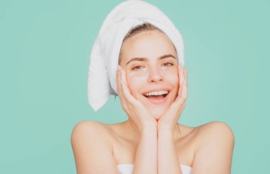 Yüz maskeli, gülümseyen bir kadın. Havluya sarılmış, yüz maskesi takan, şehvetli yüzlü, çekici bir manken. Cilt nemlendirici, krem surat..