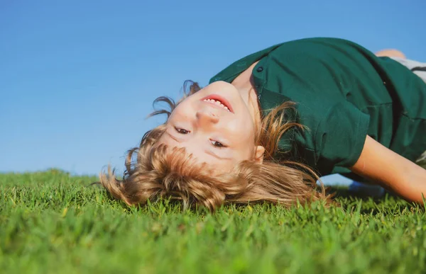 Söt, glad pojke som leker upp och ner på ett gräs i en park vid en källa. Skrattar, njuter av färskt. Roliga barn. — Stockfoto