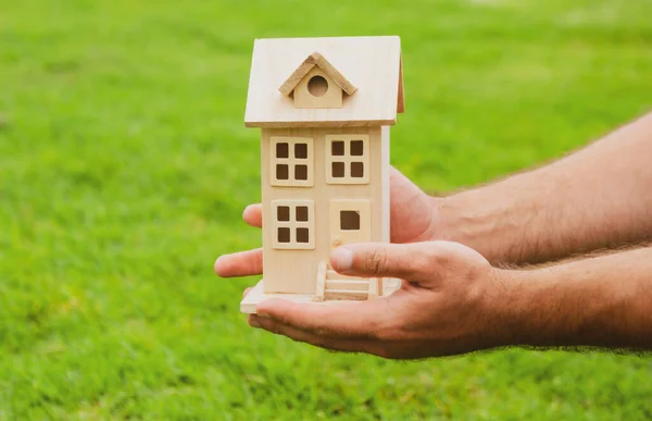 Mano sosteniendo la casa de juguete de cerca. Pequeña casa de juguete en miniatura. Hipoteca propiedad sueño mudanza casa y concepto de bienes raíces. — Foto de Stock