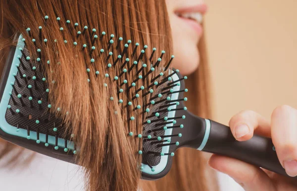 De cerca mujer sonriente cepillando el cabello con peine. Hermosa chica con cepillo de pelo largo. — Foto de Stock