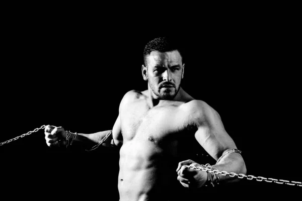 Jeune sportif avec un torse nu. Gros plan portrait d'un homme brutal seins nus avec des chaînes. Athlète gars sur fond noir. — Photo