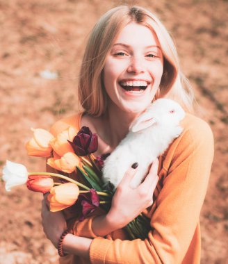 Güzel kadın beyaz tavşanı tutuyor. Tavşanla poz veren genç bir kadının portresi. Mutlu Paskalyalar.