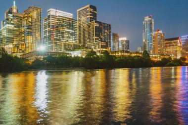 Austin, Teksas manzarası ABD şehir merkezindeki ufuk çizgisi. Gece altın günbatımı şehri. Sudaki yansıma.