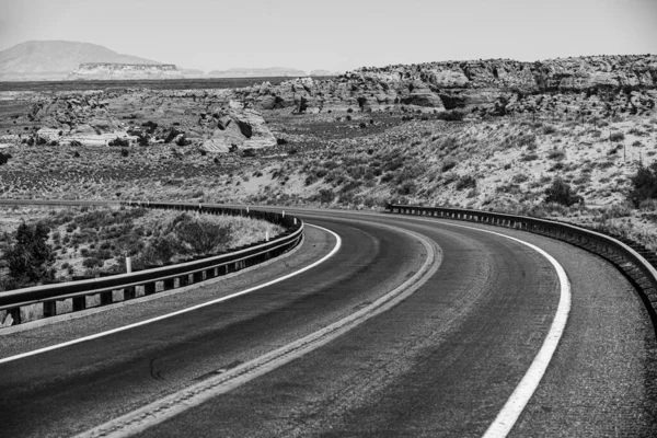 Woestijnsnelweg bij zonsondergang, reisconcept, USA. Asfalt weg en canyon achtergrond. — Stockfoto