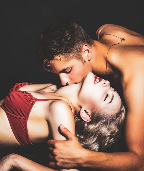 Muž líbající ženu na krk. Pár zamilovaný. Krásné rovné ženské tělo v červené podprsence se svalnatým mužem. Krásná hravá žena chce políbit muže. Nenucený styl. — Stock fotografie
