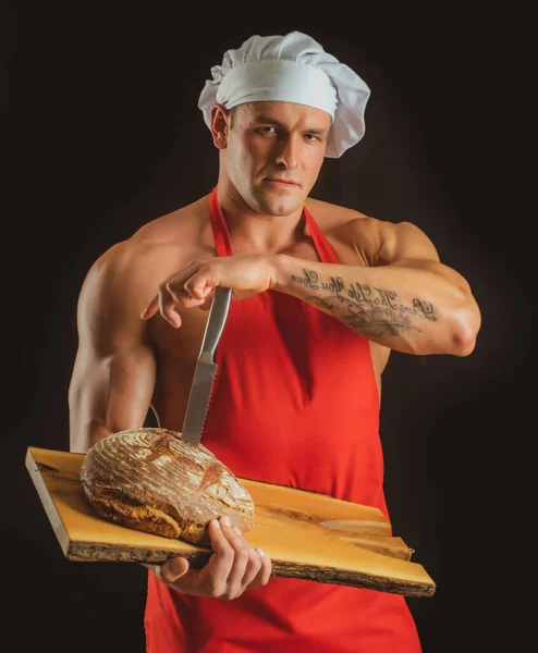 料理とベーキング.エプロンのパン屋さん。セクシー男とともにパンとナイフ. — ストック写真