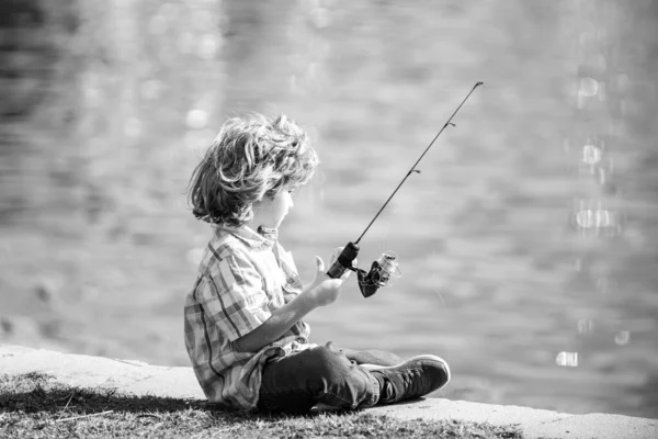 Pasatiempo de pesca. Chico con spinner en el río. Niño en embarcadero con varilla. — Foto de Stock
