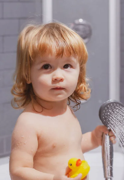 Een klein kind badend in zepen. Baby kind wassen in een badkamer in schuim. — Stockfoto