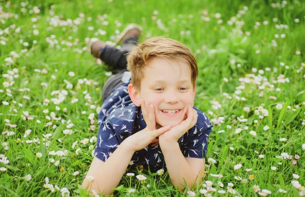 Vårpojken på gräs. Söt unge på fältsblomma. Drömmande barn. — Stockfoto