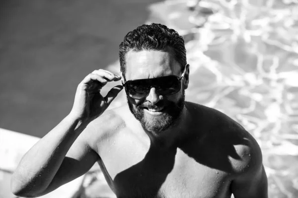 Resort de piscina de verão. Um homem bonito nas férias de verão. Homem de óculos de sol relaxante na piscina. — Fotografia de Stock