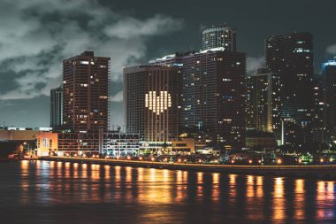 Miami gecesi şehir merkezinde, Florida 'da. Günbatımında Miami Florida, aydınlık binaların ufuk çizgisi ve Macarthur Köprüsü.