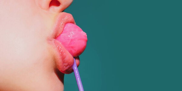 Леденец во рту женщины, красная помада. Женщина лижет красный блестящий леденец. Закрывай. Сексуальная женщина с леденцом во рту.