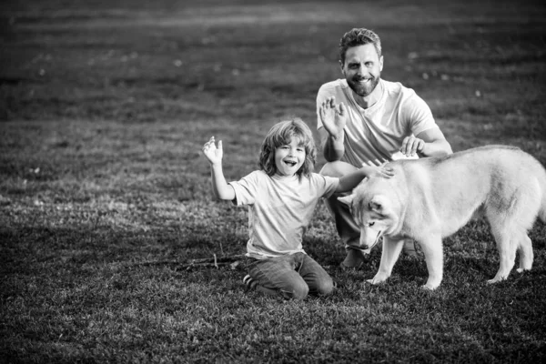 Glücklicher Vater und Sohn mit Hund im Park. Wochenendaktivitäten glücklich Familie Lifestyle-Konzept. — Stockfoto