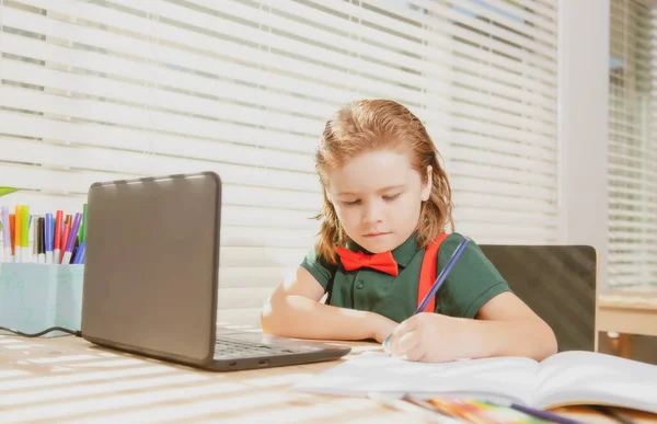 Seriös skolpojke koncentrerade sig på att rita när han satt nära laptop hemma. — Stockfoto