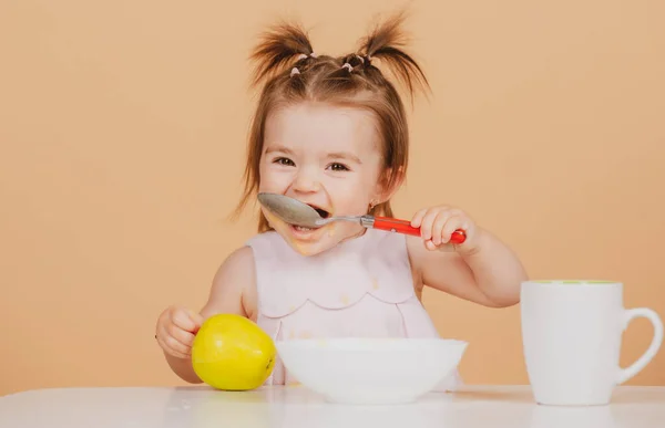 Çocuk sağlıklı besleniyor, bebek maması yiyor. Kaşıkla yiyen bebekler. Bebeklerin ilk yemeği. Çocuk tek başına kaşık ve tabakla yemek yiyor.. — Stok fotoğraf