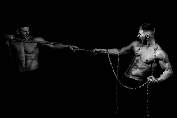 Deux hommes ont cassé des chaînes, tenant la chaîne. Torse sexy de jeune homme de remise en forme avec des muscles abdominaux et pectoraux forts musculaires et un sein puissant. Isolé sur noir. — Photo