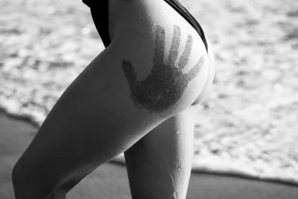 Nahaufnahme weiblicher Hintern mit sandfarbenen Handabdrücken in Miami oder Teneriffa. Sommer Frau sexy Gesäß mit muskulösem Körper. Frau Badeanzug und Dessous-Konzept. Leidenschaft und sinnlicher Touch. — Stockfoto