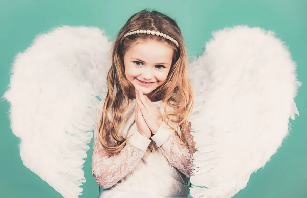 Piękna mała aniołeczka. Złośliwa mała anielska dziewczynka stojąca z twoimi zaciśniętymi pięściami. Piękna mała aniołek dziewczyna stojąca z ramionami blisko klatki piersiowej jak w modlitwie. — Zdjęcie stockowe